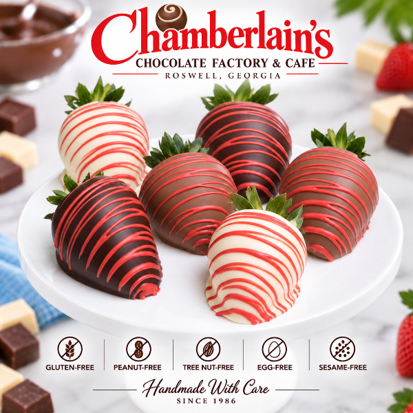Half dozen red and pink drizzled chocolate covered strawberries on a white cake stand — dark and white chocolate dipped, crafted at Chamberlain's Chocolate Factory in Roswell, Georgia