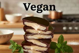Allergen Friendly Dark Vegan Chocolate Mint Cups stacked with mint leaves on a kitchen counter.