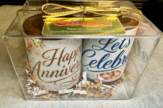 Anniversary chocolate shot glasses gift set of 2 in a clear gift box with Chamberlain's Chocolate Factory label, Roswell Georgia, gold ribbon bow, edible floral 'Happy Anniversary' and 'Let's Celebrate' prints with wedding ring design