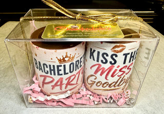 Bachelorette party chocolate shot glasses gift set of 2 in a clear gift box with Chamberlain's Chocolate Factory label, Roswell Georgia, gold ribbon bow, edible 'Bachelorette Party' crown and 'Kiss the Miss Goodbye' lip print designs