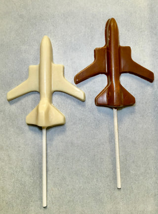 Two airplane-shaped chocolate lollipops. One lollipop is white chocolate and the other is milk chocolate. 