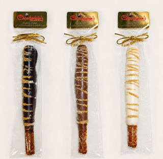 Three packaged chocolate-covered pretzel rods, each in a clear bag with a gold bow. Chamberlains Chocolate Factory in Atlanta