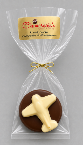 A round chocolate Oreo with a white chocolate airplane, individually wrapped in a clear cellophane bag with a Gold ribbon and a Gold label from Chamberlain's Chocolate