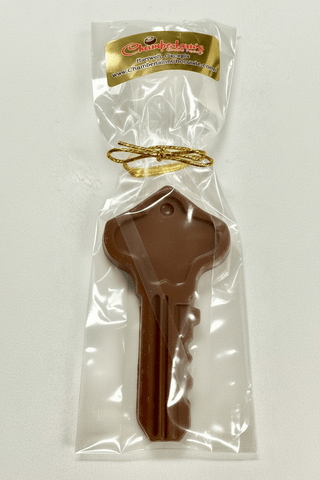 Chocolate key shaped like a house key in clear packaging with a brand label on a white background