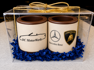 Set of 2 custom chocolate shot glasses with edible company logo in blue crinkle paper in a clear acrylic gift box with gold bow, corporate client gift by Chamberlain's Chocolate, Atlanta GA