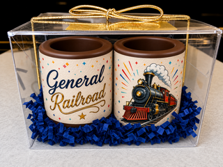 Set of 2 custom branded milk chocolate shot glasses with edible logo print and colorful design, nestled in blue crinkle paper in a clear acrylic gift box with gold bow, corporate gift by Chamberlain's Chocolate, Roswell GA