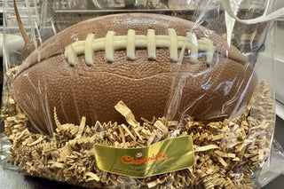 Milk Chocolate Life Size Football in a gift bag with shredded paper, featuring white chocolate strings.