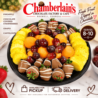 Fresh fruit platter with chocolate covered strawberries, pineapple, cantaloupe, and grapes on a black round tray — serves 8 to 10, available for local pickup and delivery from Chamberlain's Chocolate Factory in Roswell, Georgia