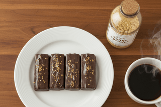 Allergen Friendly Vegan Keto Dark Chocolate Maple Bars on a plate with maple sprinkle jar and coffee cup.