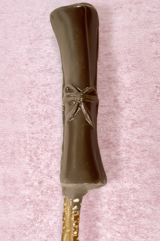 Graduation Chocolate Covered Pretzel Rods decorated with dark chocolate and a bow design.