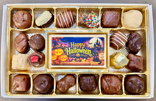 Open assortment with “Happy Halloween” image: “Open Halloween chocolate assortment with Happy Halloween edible image bar surrounded by assorted chocolates