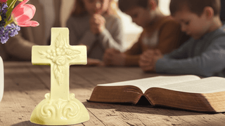 Hand Molded Elaborate Chocolate Cross Boxed Gift in a prayerful setting with children and an open Bible.