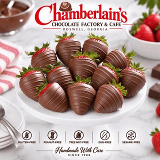 One dozen milk chocolate covered strawberries with chocolate drizzle piled on a white marble cake stand — classic chocolate strawberry gift box from Chamberlain's Chocolate Factory"
