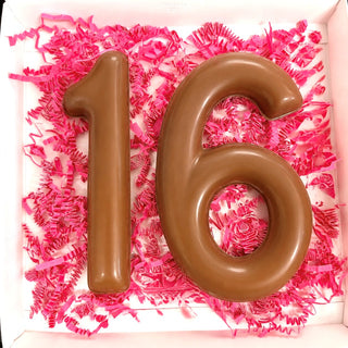 Open gift box with molded milk chocolate number 16 nestled in hot pink paper shred, sweet sixteen birthday chocolate gift from Chamberlain's Chocolate Factory

