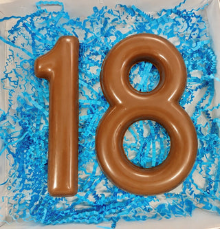 Open gift box with molded milk chocolate number 18 nestled in blue paper shred, 18th birthday or graduation chocolate gift from Chamberlain's Chocolate Factory

