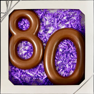 Chamberlain's custom number chocolate gift box with molded milk chocolate number 80 in purple paper shred, tied with a silver ribbon bow, 80th birthday gift

