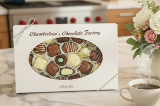 Chamberlain's Chocolate One Pound Classic Assortment Box with coffee and flowers on a marble countertop.