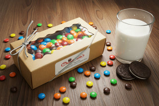 Chocolate Molded Oreos with M&M Candies in a gift box with a glass of milk and colorful candies scattered.