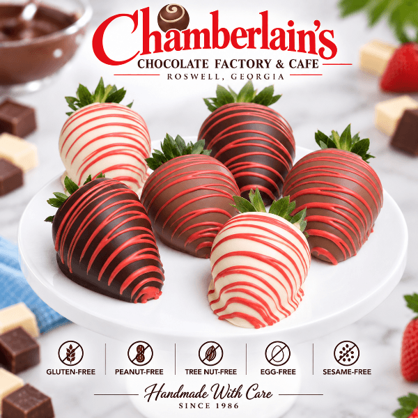 Half dozen red and pink drizzled chocolate covered strawberries on a white cake stand — dark and white chocolate dipped, crafted at Chamberlain's Chocolate Factory in Roswell, Georgia