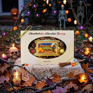 A Halloween-themed chocolate gift box from Chamberlain's Chocolate Factory, displayed in a spooky outdoor setting with candles, autumn leaves, and string lights.